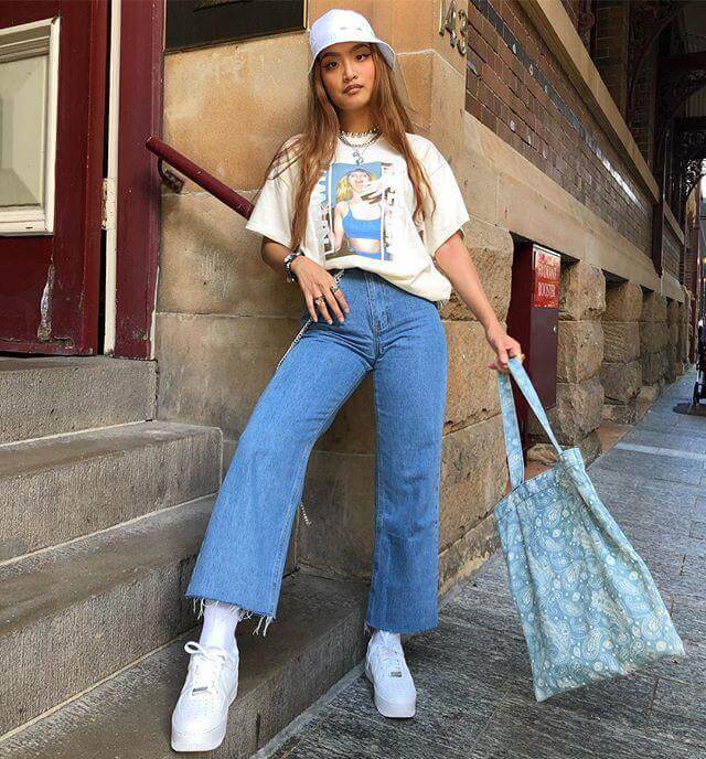 Chica luciendo un gorro blanco, camiseta beige, jean denim azul, zapatos blancos y bolsa de mano verde claro